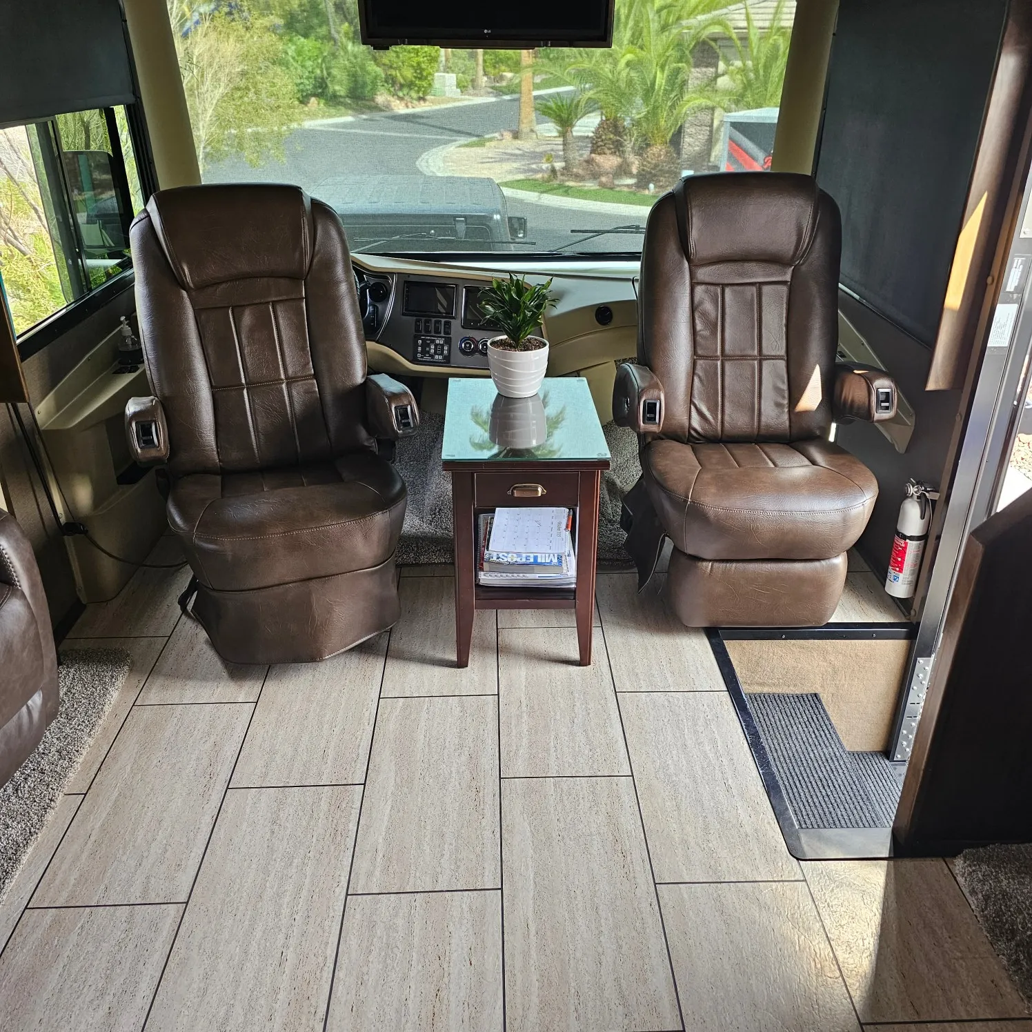 Interior of an RV with two brown leather chairs and a table in the center