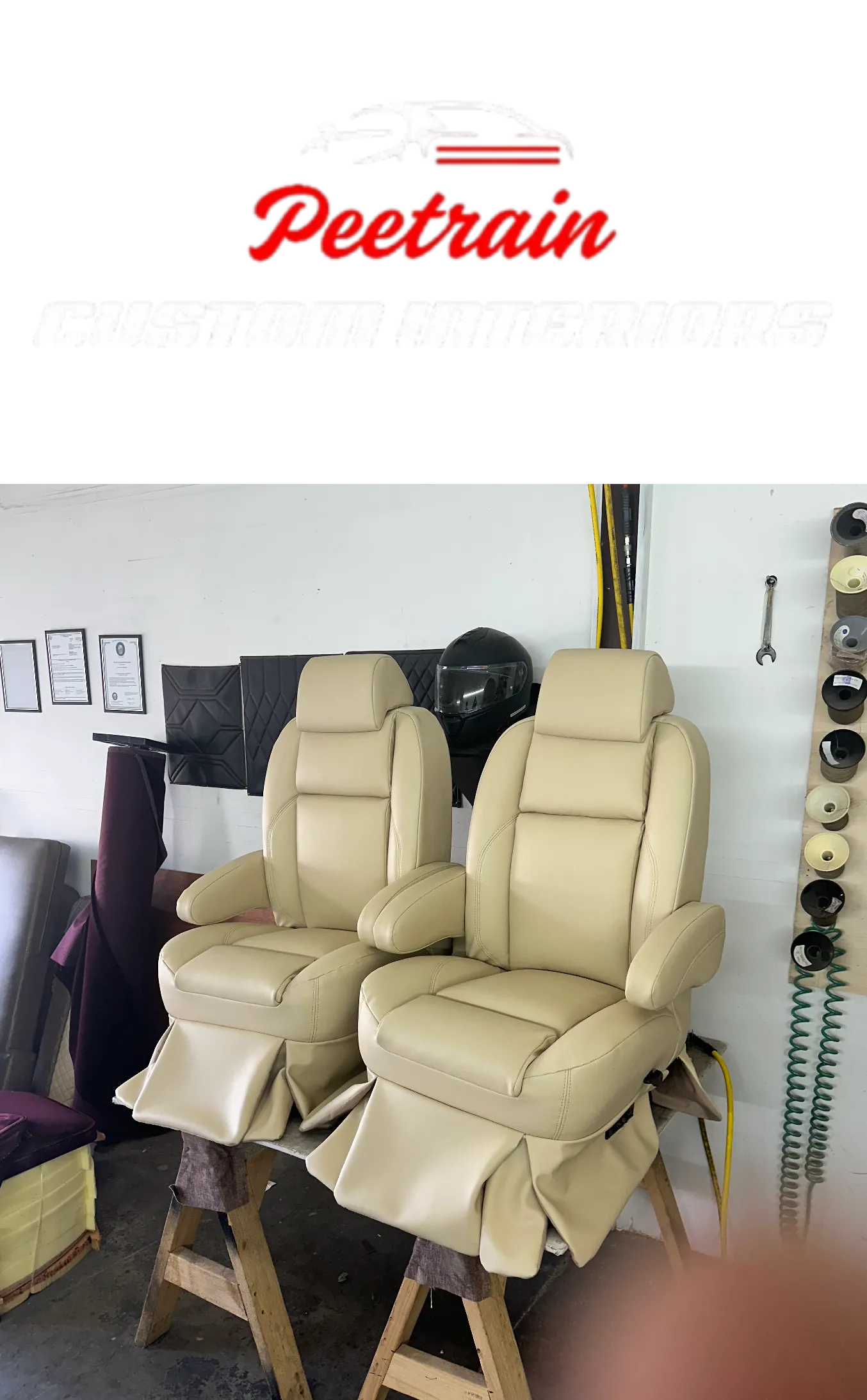 Pair of custom leather car seat covers in a garage, with a wall in the background adorned with photo frames