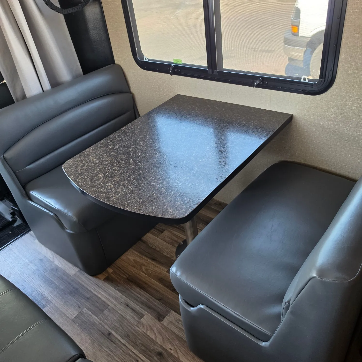 2019 -Lite travel trailer with a table and two chairs in the center, a window