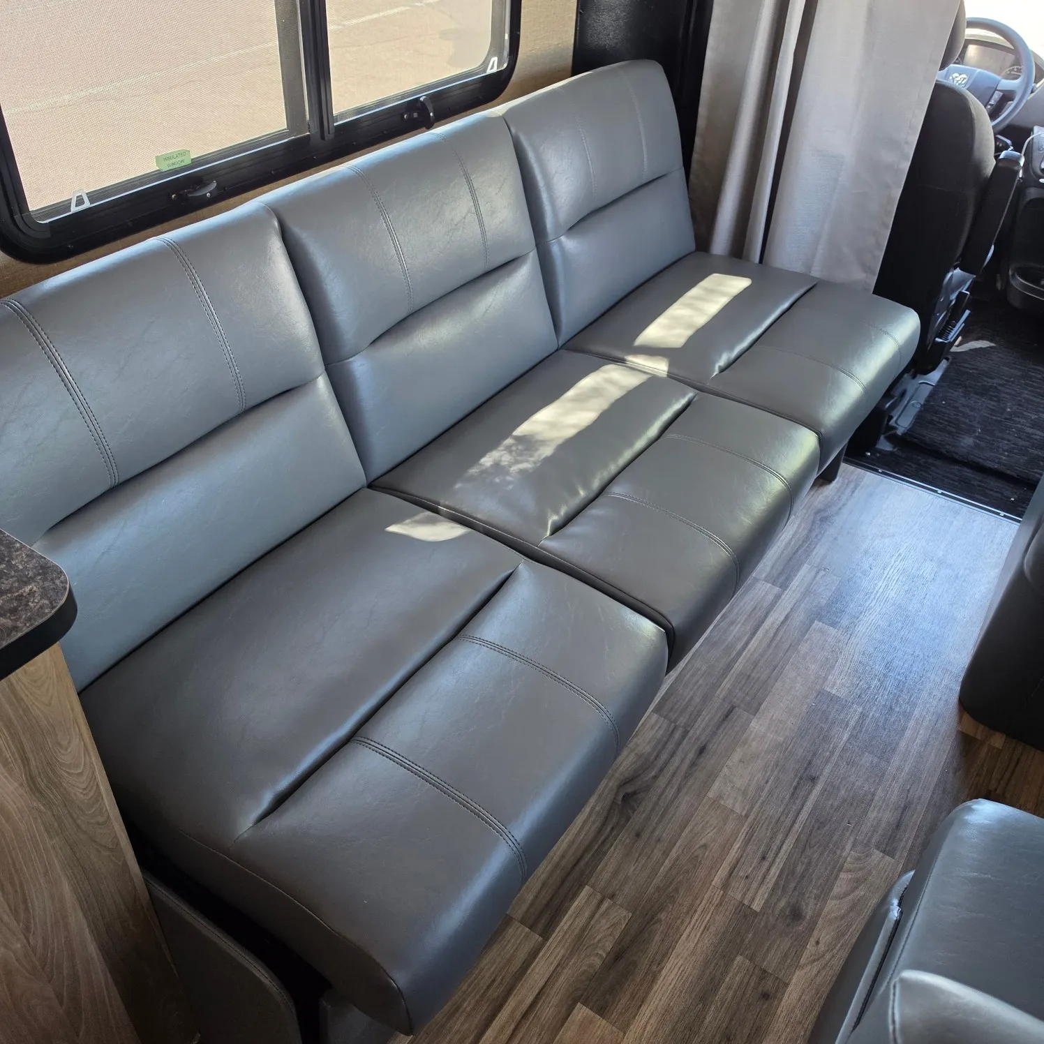 Interior of a 2019 RV, with a comfortable couch, a steering wheel, curtains, and glass windows